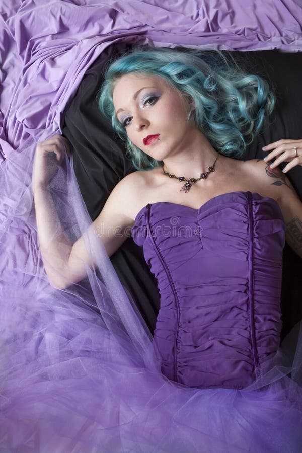 Pretty young woman with blue hair and wearing purple corset and tulle skirt lying on floor. Pretty young woman with blue hair and wearing purple corset and tulle skirt lying on floor