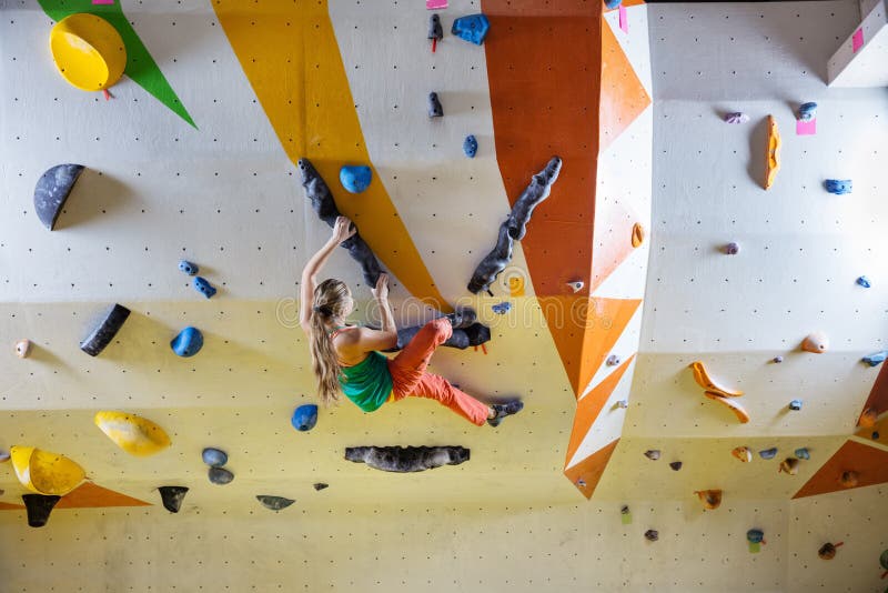 Young woman bouldering in climbing gym