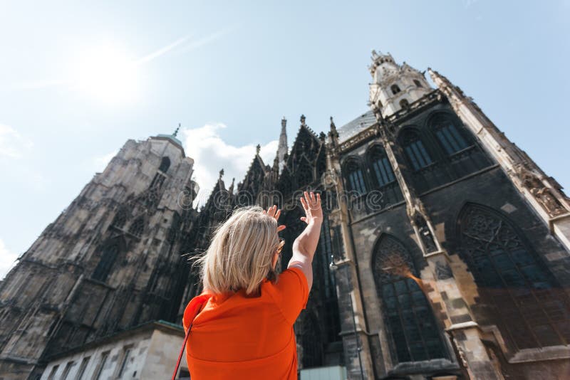 A young woman in a bright orange dress stands on the background of St. Stephen`s Cathedral in Vienna, Austria stock photography A young woman in a bright orange dress stands on the background of St. Stephen`s Cathedral in Vienna, Austria stock photography