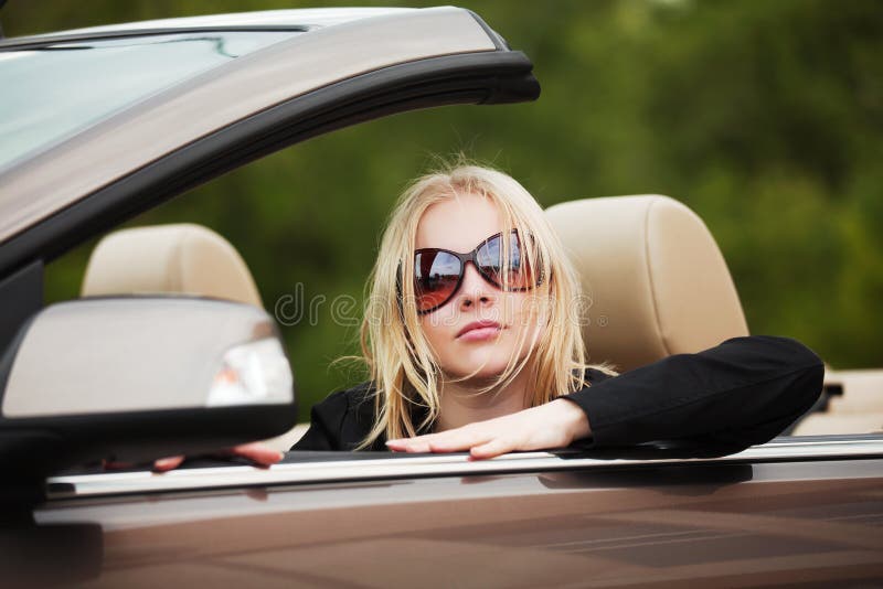 Mladý móda blondýnka žena v sluneční brýle řízení kabriolet auto.