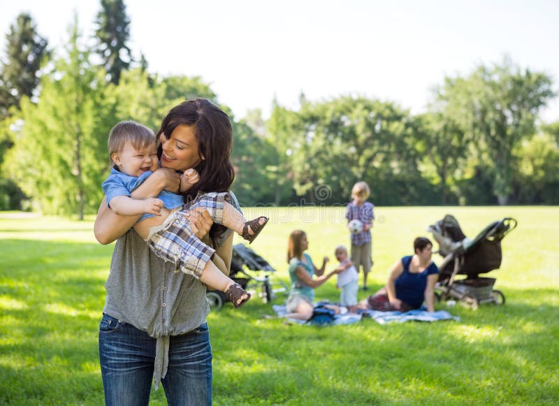 Young Woman Carrying Baby Boy In Park