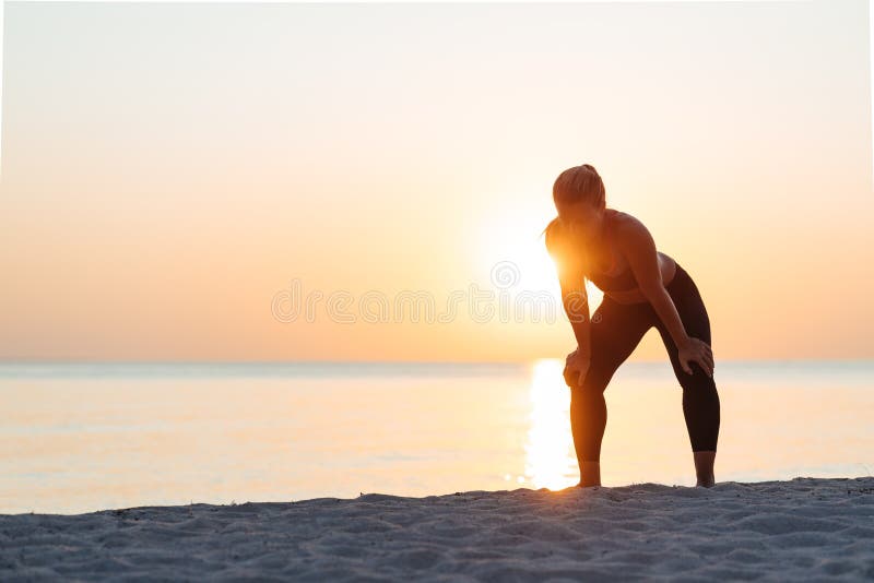 Young woman catching a breath after a run on the beach stock photo Young woman catching a breath after a run on the beach stock photo