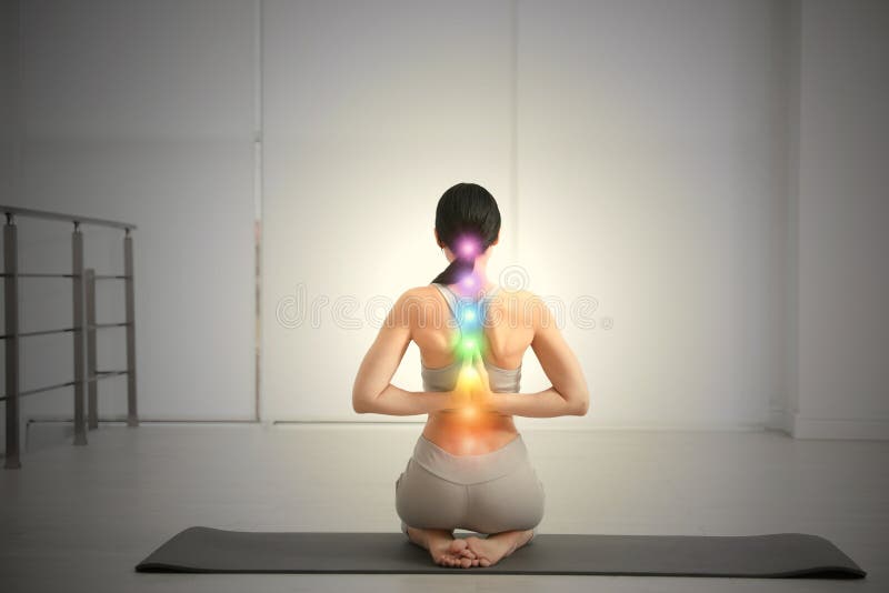 Young woman with chakra points practicing yoga, back view. Healing energy