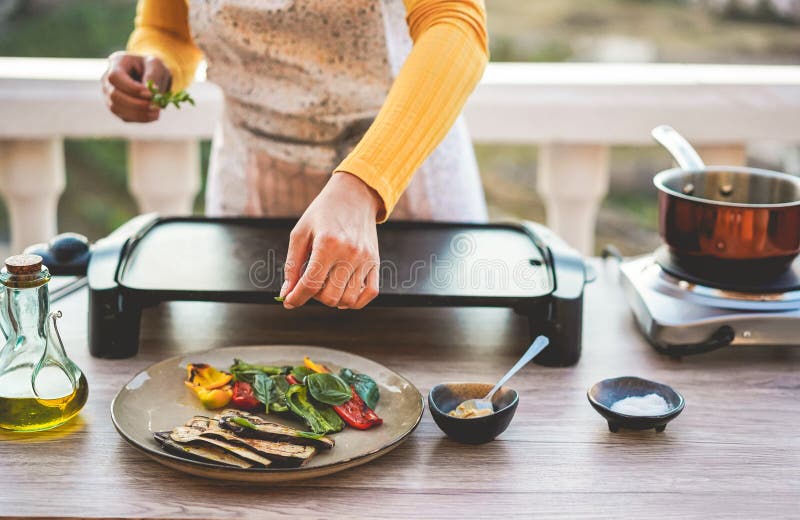 Young woman chef cooking outdoor while streaming online for webinar masterclass lesson at home during isolation quarantine - Food. Concept - Main focus on close royalty free stock photo Young woman chef cooking outdoor while streaming online for webinar masterclass lesson at home during isolation quarantine - Food. Concept - Main focus on close royalty free stock photo