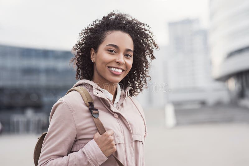 Young woman in a city looking at camera. African-american student girl portrait. Cute girl smiling. stock photos