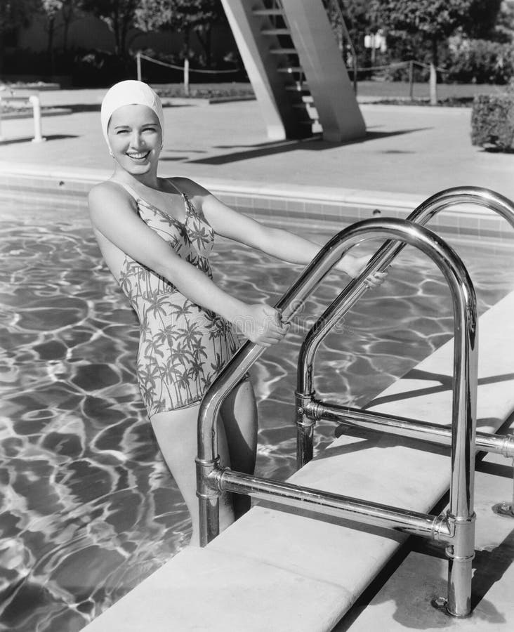 Young woman climbing up the ladder of a swimming pool