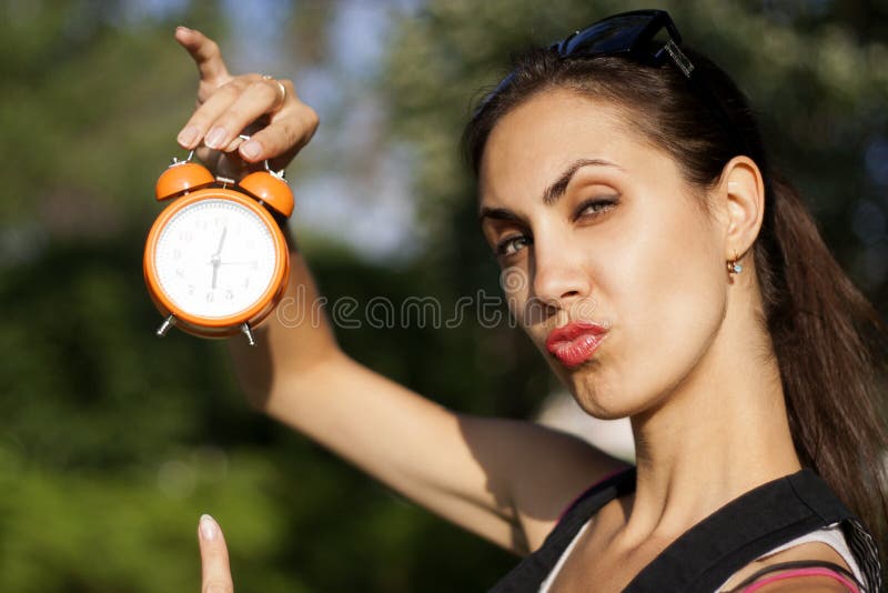 Young woman with clock outdoors