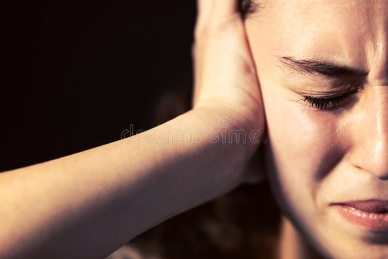 A young woman close-up with headache on black background. Mental illness concept