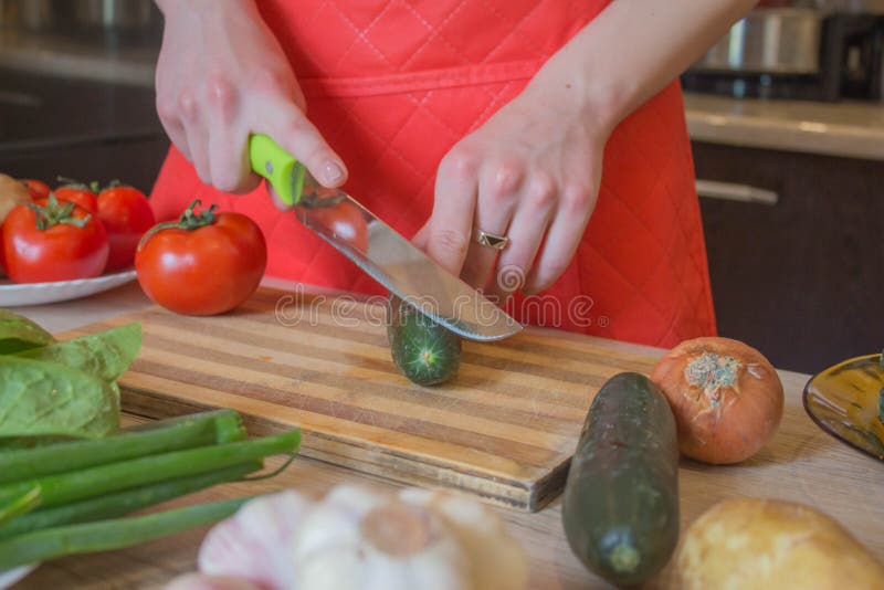 Young woman cooking healthy meal in the kitchen. Cooking healthy food at home. Woman in kitchen preparing vegetables. Chef cuts royalty free stock image Young woman cooking healthy meal in the kitchen. Cooking healthy food at home. Woman in kitchen preparing vegetables. Chef cuts royalty free stock image