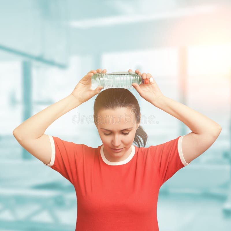Woman Holding a Cold Water Bottle on Her Forehead. Eyes Closed. Stock