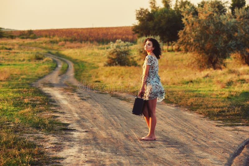 Young woman on country road with suitcase stock photos Young woman on country road with suitcase stock photos