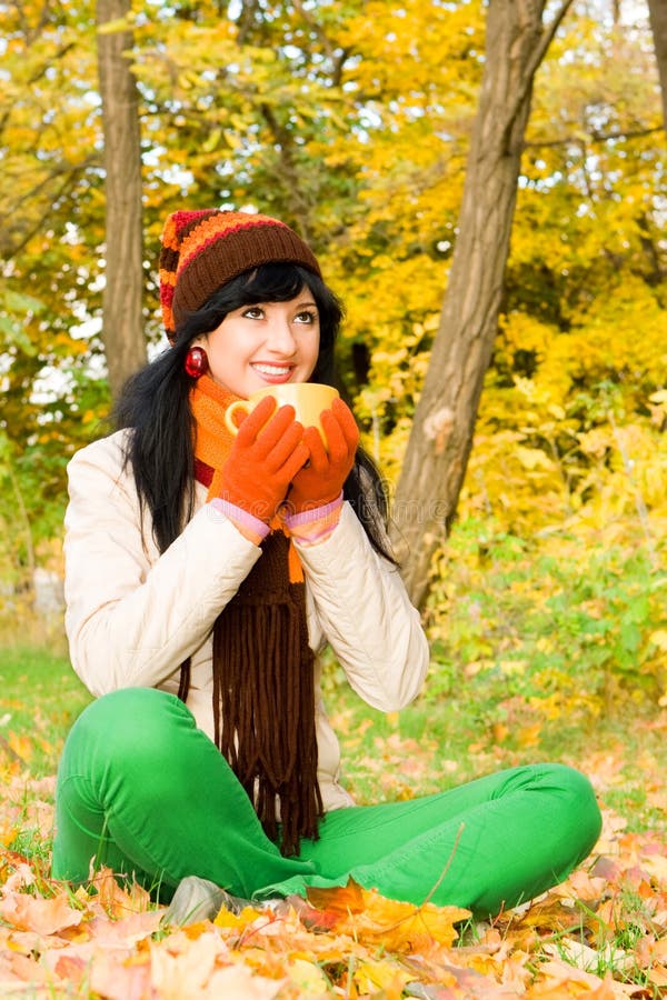 Young woman with cup of tea in the autumn park