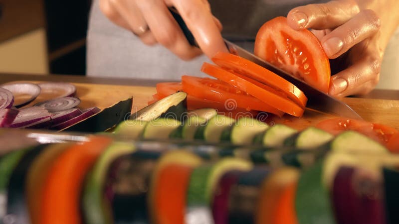 Young woman cutting juicy red tomato. Cooking homemade ratatouille. Young woman cutting red tomato. Cooking ratatouille stock images Young woman cutting juicy red tomato. Cooking homemade ratatouille. Young woman cutting red tomato. Cooking ratatouille stock images