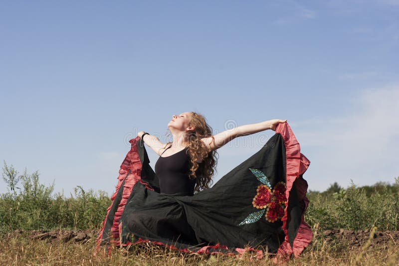 Young woman dancing outdoors in long skirt