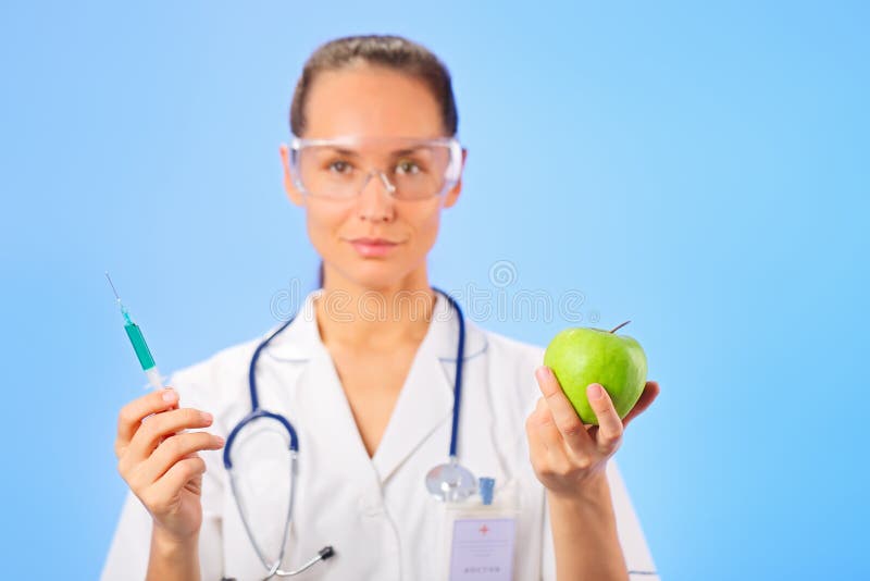 Young woman doctor injecting green apple