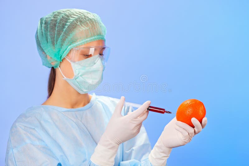 Young woman doctor injecting orange fruit