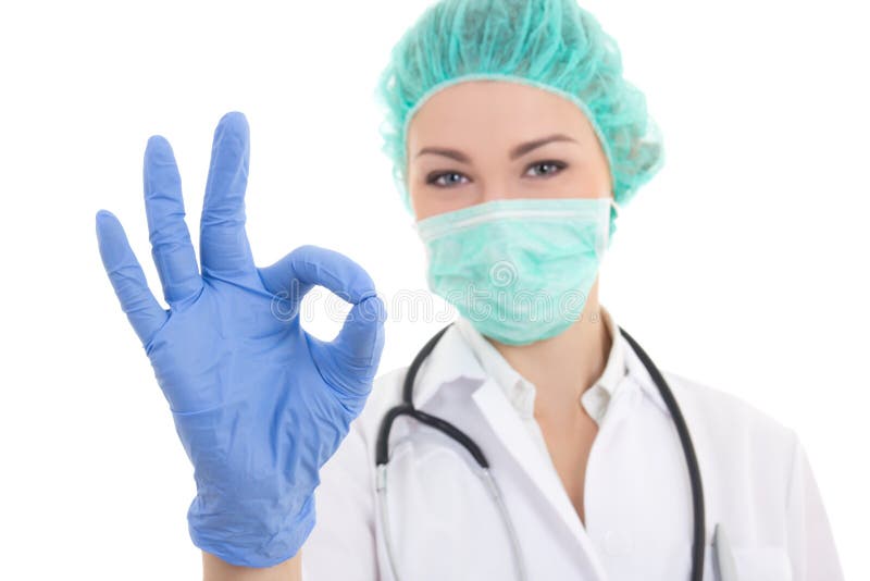 young woman doctor in surgeon mask, cap and rubber gloves showing ok sign isolated on white