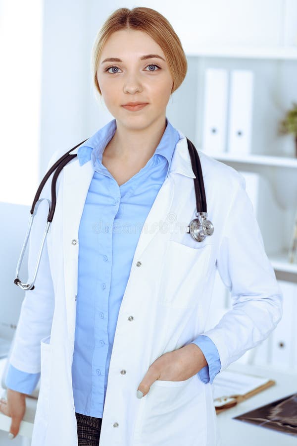 Young Woman Doctor at Work in Hospital Looking at Camera. Blue Colored ...