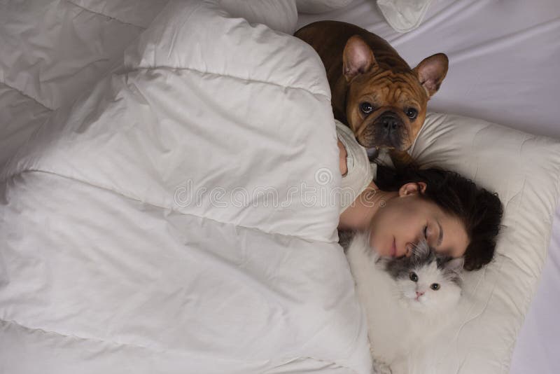 Young woman with dog and cat bask in the morning in her bed