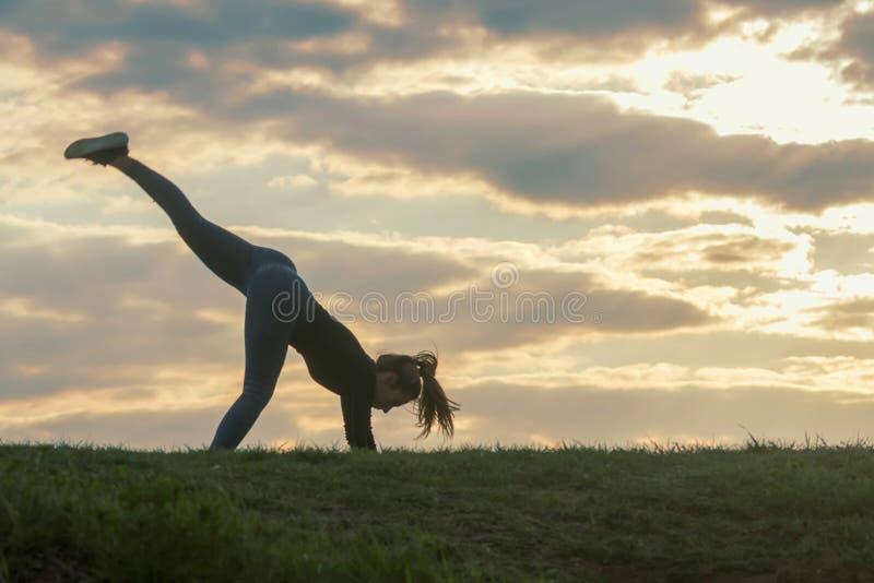 Young woman doing cartwheel on the grass Morning workout beautiful sunrise stock photo Young woman doing cartwheel on the grass Morning workout beautiful sunrise stock photo