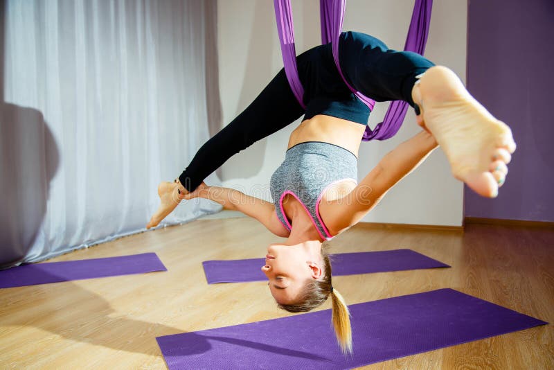 Young woman doing stretching and twine. Aerial yoga exercise or antigravity yoga indoor. Fitness, stretch, balance, exercise and h