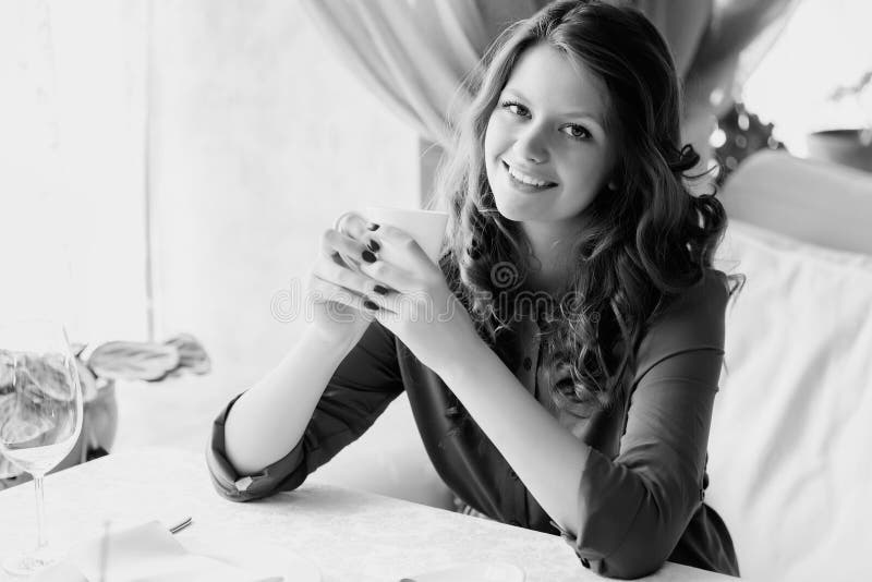 Young woman drinking coffee in a cafe. Black and white photo. stock images
