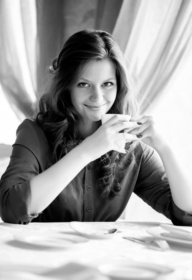 Young woman drinking coffee in a cafe. Black and white photo. royalty free stock photos