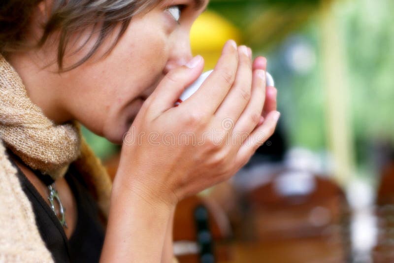 Young woman drinking hot coffee at cafe