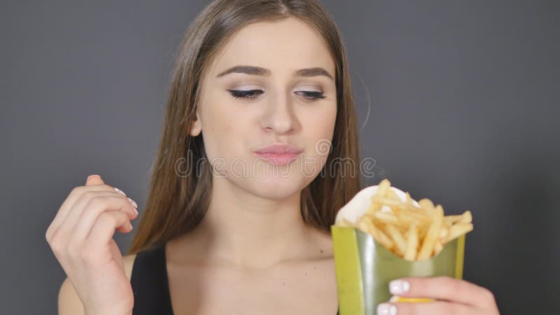 Young woman eating french fries close detail