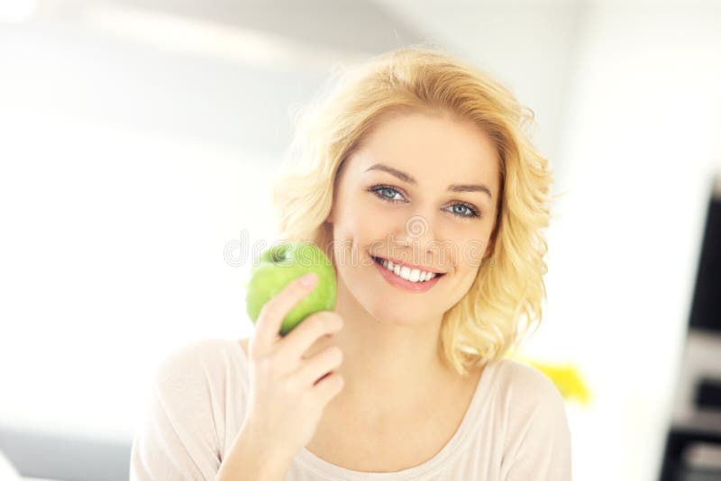 Young woman eating a green apple at home stock photography Young woman eating a green apple at home stock photography