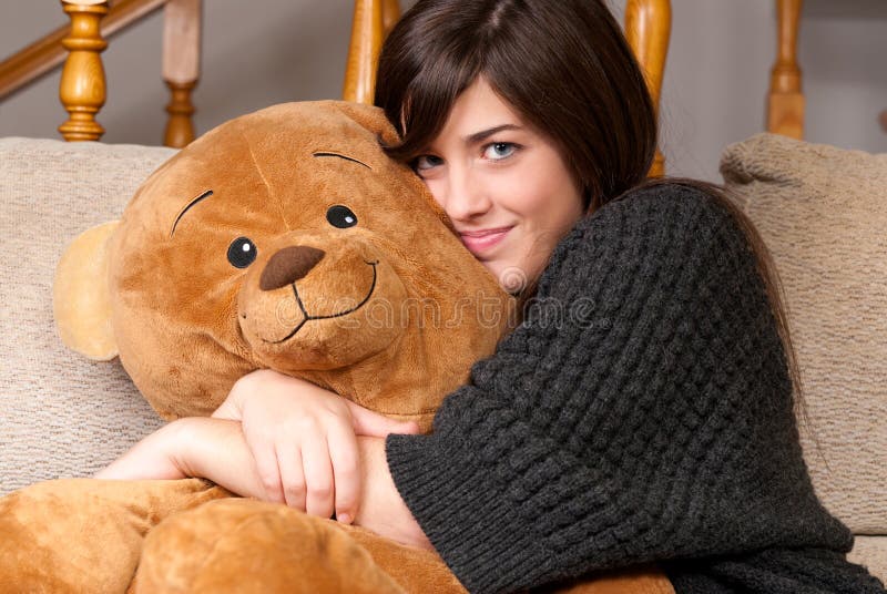 Young woman embrace teddy bear sitting sofa close