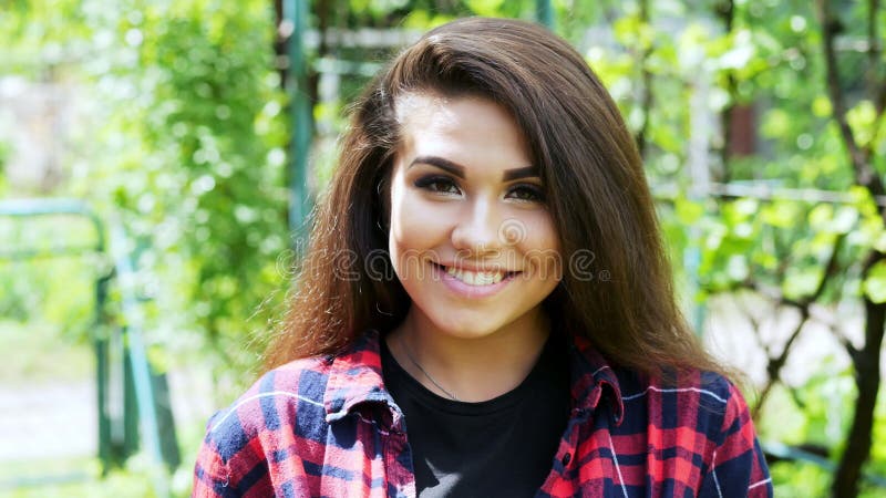 Young woman enjoying summer time in the garden, happy girl smiling and looking at the camera