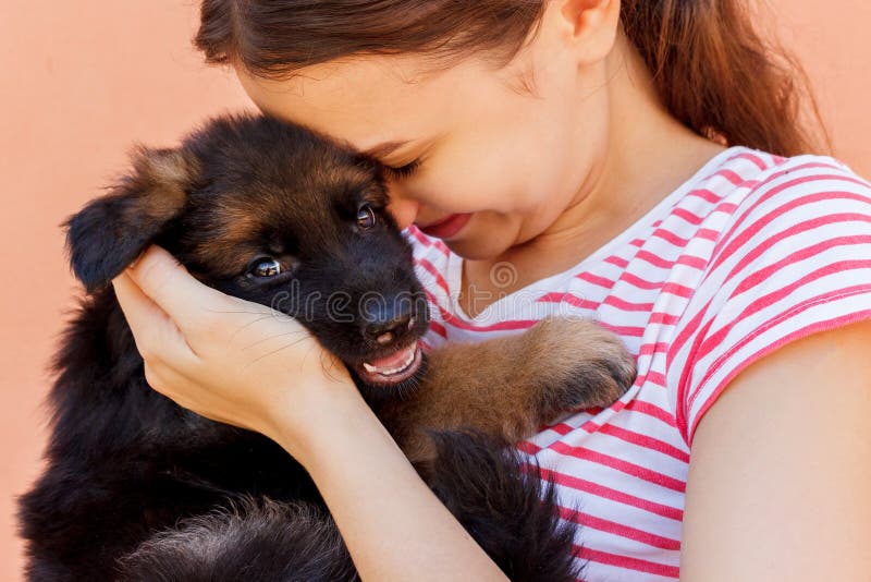 Young woman enjoys hugging a small cute puppy stock image Young woman enjoys hugging a small cute puppy stock image