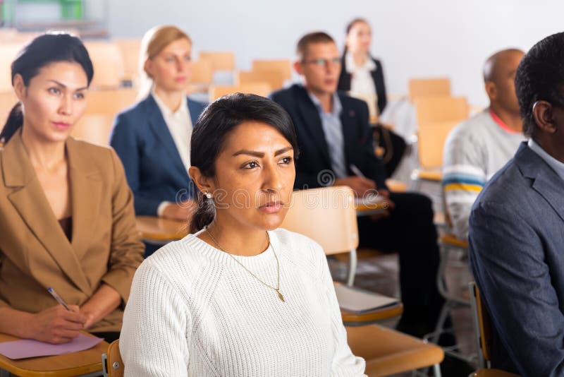 Confident woman listening to lecture at conference stock image