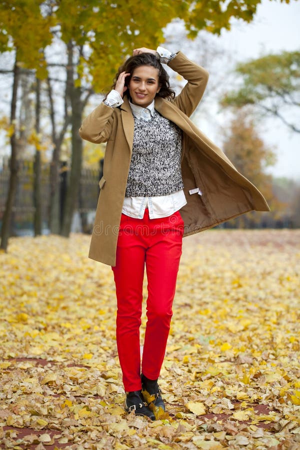 Young woman in fashion coat walking in autumn park