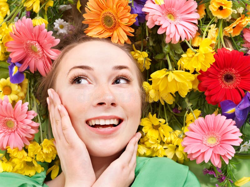 Young woman in flowers touching face. stock photos