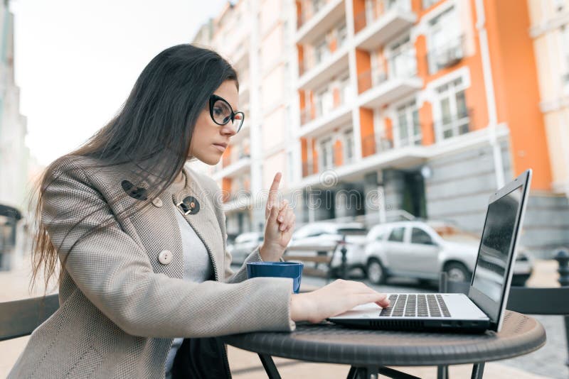Young woman gesturing index finger up looking into a laptop computer. Attention, idea, eureka stock images Young woman gesturing index finger up looking into a laptop computer. Attention, idea, eureka stock images