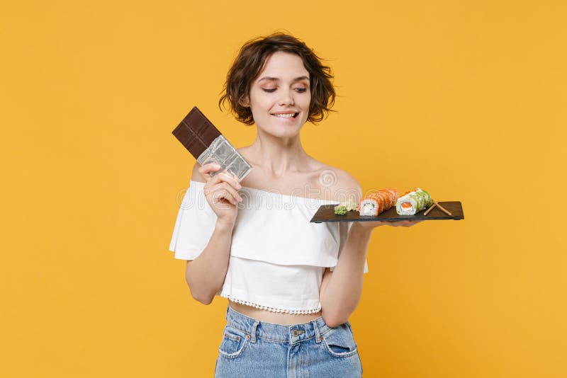 Young woman girl hold in hand choice between chocolate bar makizushi sushi roll served on black plate traditional royalty free stock photos