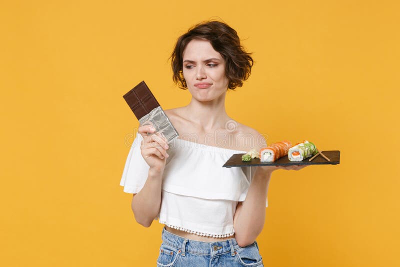 Young woman girl hold in hand choice between chocolate bar makizushi sushi roll served on black plate traditional royalty free stock photo
