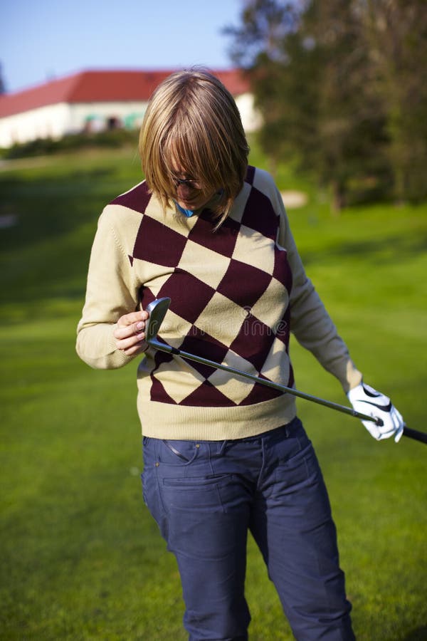 Young woman golfer examining her golf club