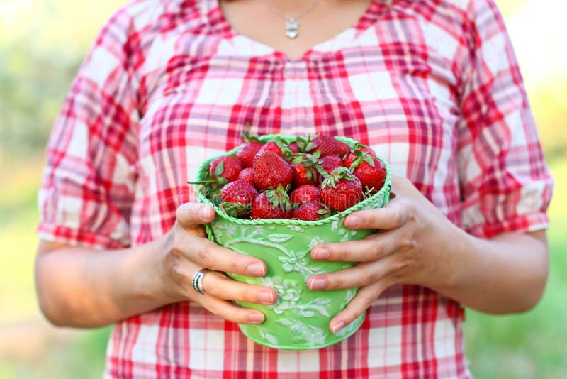 Young woman with a green pail of strawberries outdoors royalty free stock photo
