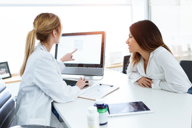 Young woman gynecologist doctor showing to patient some information in computer in medical consultation