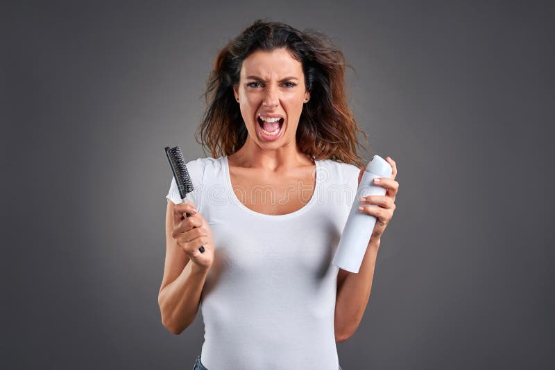 A beautiful young woman screaming while brushing her hair and holding a hairspray.r. A beautiful young woman screaming while brushing her hair and holding a hairspray.r