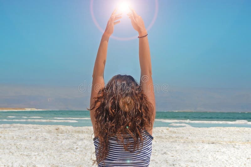 Young woman hands catching the energy of the sun. long-haired girl sits on the shore of the Dead Sea in Israel stock image Young woman hands catching the energy of the sun. long-haired girl sits on the shore of the Dead Sea in Israel stock image