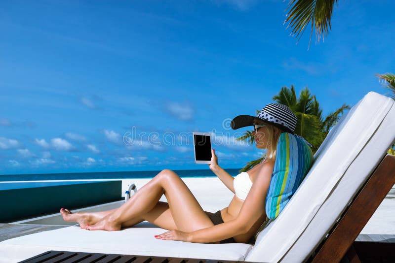 Young woman in hat with tablet pc at the beach