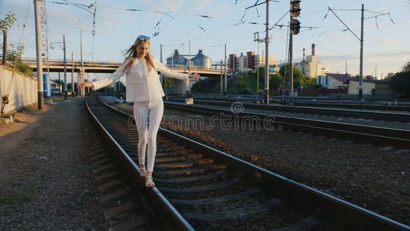 Young woman having fun. Walks by rail to rail, laughing