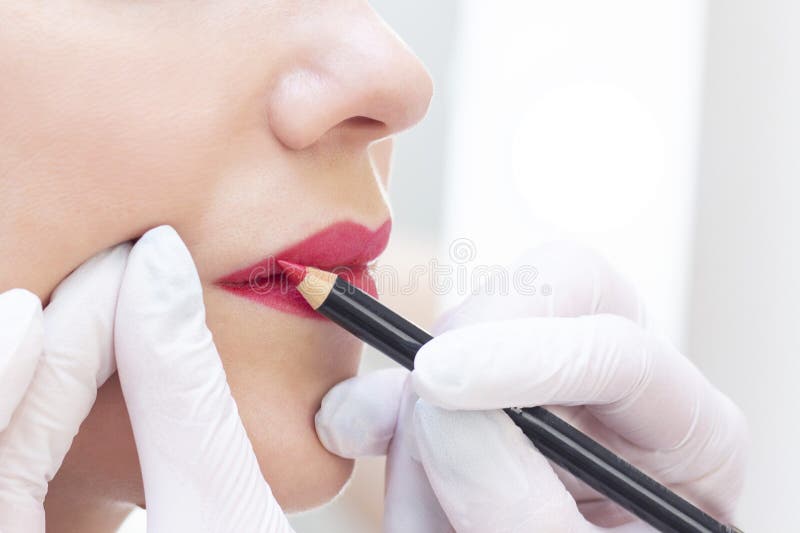 Young woman having permanent makeup on her lips at the beauticians salon.