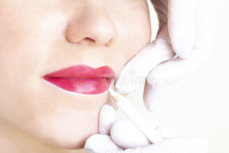 Young woman having permanent makeup on her lips at the beauticians salon.