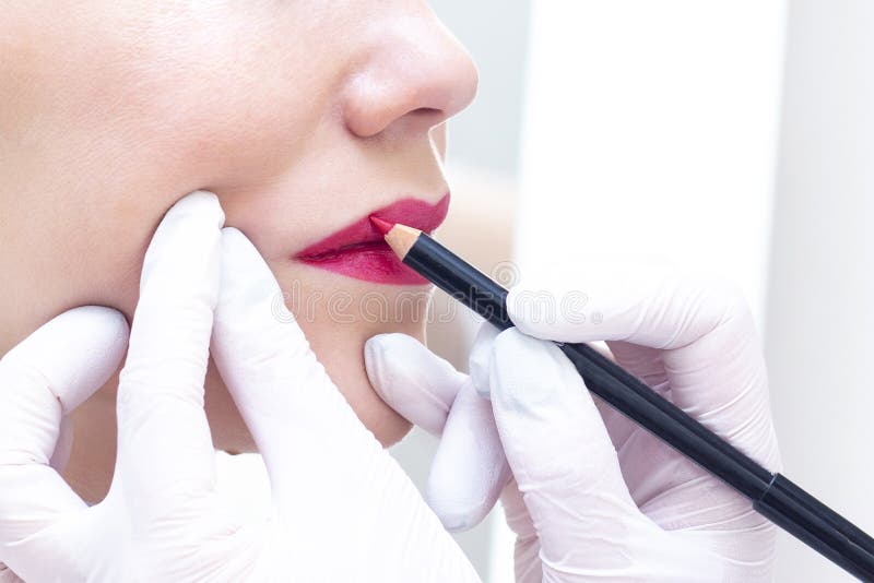 Young woman having permanent makeup on her lips at the beauticians salon.