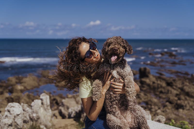 Young woman and her cute spanish water dog outdoors enjoying together on a sunny and windy day. Summertime, love for animals and stock photo Young woman and her cute spanish water dog outdoors enjoying together on a sunny and windy day. Summertime, love for animals and stock photo